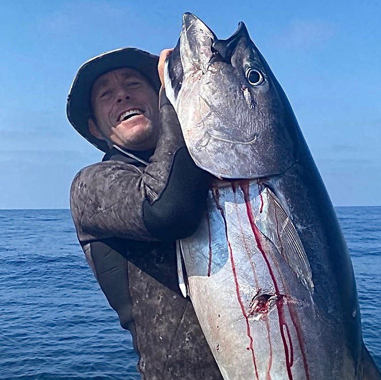 Colin Smith (man) holding a big tuna caught with a spear gun. Wearing a shelta sun hat