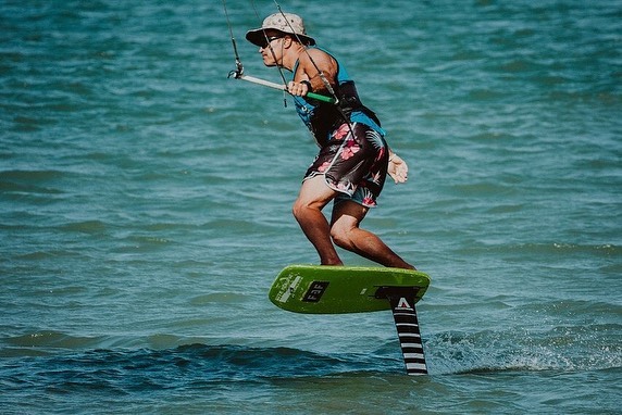 Picture of a kite surfer wearing a shelta sun hat made for kite surfing. Foil board