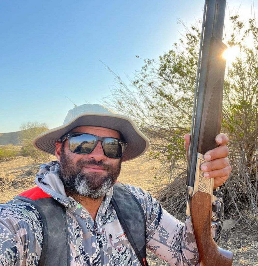 Man wearing the Firebird sun hat holding a hunting rifle