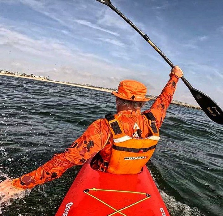 Picure of kayak paddler from the back wearing Orange Osprey Sun hat. The best sun hat for water sports